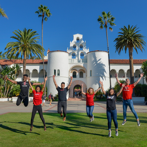 Happy students jumping in the air in front of Hepner Hall.
